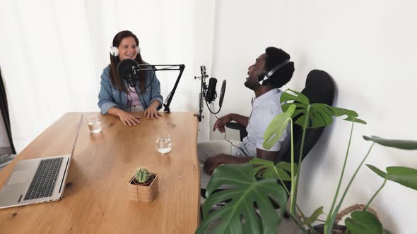 Multiracial people recording a podcast using microphone and laptop from home studio