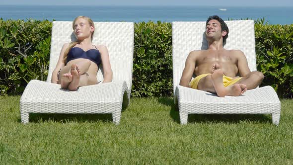 Young couple on sun loungers holding hands