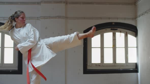 Side View of Focused Karateka Doing Kicking with Twist in Gym