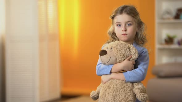 Abandoned Upset Curly Girl Holding Favorite Teddy Bear Feeling Sad in Orphanage