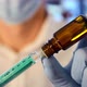 Researcher with face mask and blue gloves fills syringe with vaccine.  - VideoHive Item for Sale