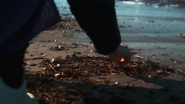 Shot of Woman Crouching and Sifting Through the Sticks Using a Stick