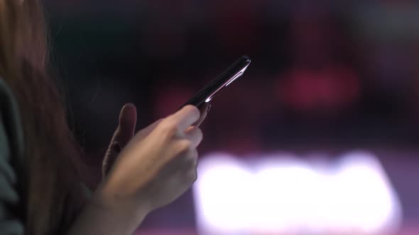 Female Hands Holding a Phone on a Dark Background
