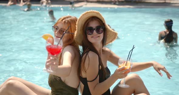 Female Friends Enjoying Drinks Standing at Pool