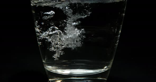 Water being poured into Glass against Black Background, Slow Motion 4K