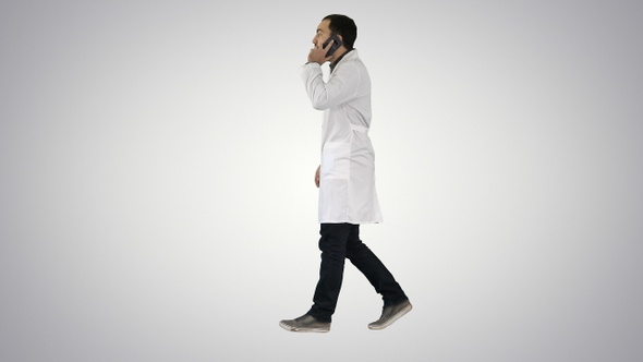 Young Doctor Talking to Mobile and Walking on Gradient Background