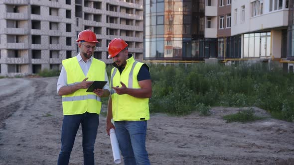 Two Engineers Using a Black Tablet in the House Building