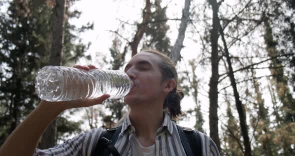 Man drinking water in nature and looking at camera.