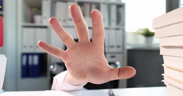 Man Hand Reaches Out From Under Table on Which Lot of Business Documents Lie