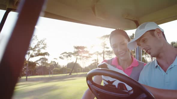 Golfers sitting in golf buggy using mobile phone