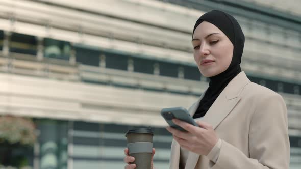 Arabian Woman Walking Outdoors with Cell Phone and Coffee