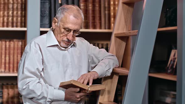 Elderly 70s Male University Professor Reading Book Searching Information Lecture at Public Library