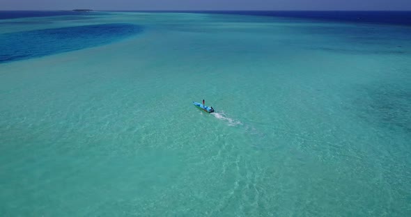 Wide flying clean view of a sandy white paradise beach and aqua blue water background in colorful 4K