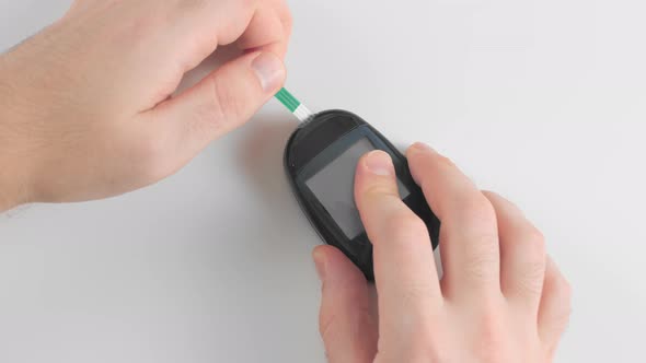 Unrecognized Man Prepares a Glucose Meter To Measure Blood Glucose, Sugar Levels, for Measurements