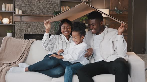 African Couple Sitting on Couch Under Cardboard Roof Smiling Looking at Camera Active Happy Daughter