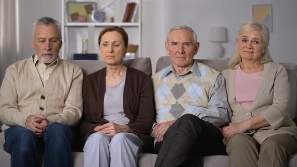 Upset Senior Friends Sitting on Sofa and Looking at Camera, Social Problems