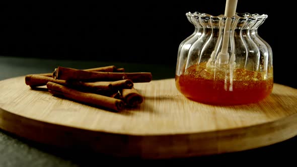 Cinnamon sticks and honey on heart shape board