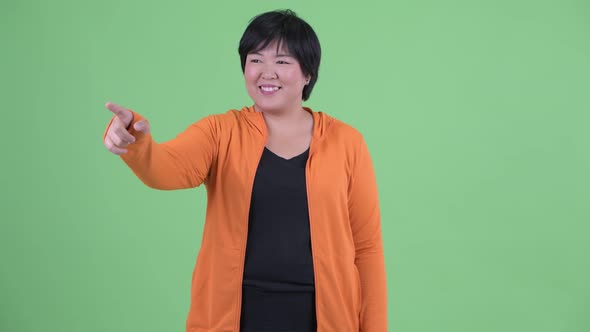 Happy Young Overweight Asian Woman Pointing Finger Ready for Gym