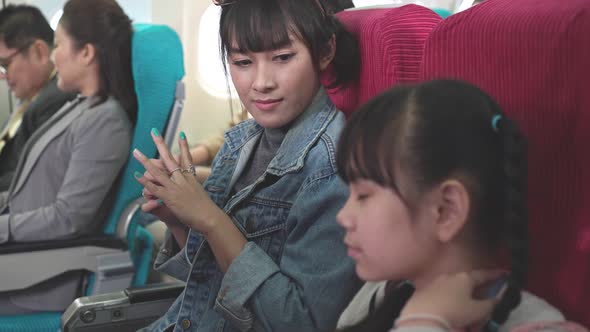 Asian mother sitting and talking with daughter on airplane seat