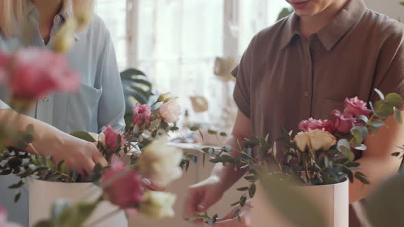 Two Women Arranging Flower Composition in Hatboxes during Masterclass