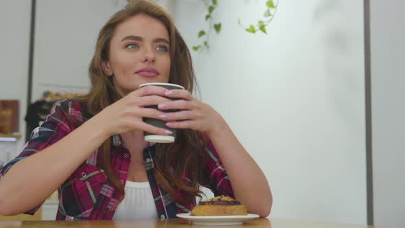 Beautiful woman in cafe drinking coffee with dessert. 