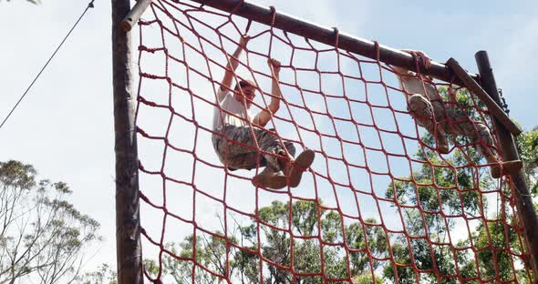 Military troops climbing a net during obstacle course