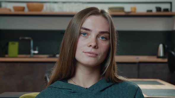 Close-up Portrait of Young Woman with Beautiful Blue Eyes Looking at Camera Sit on Sofa Alone at