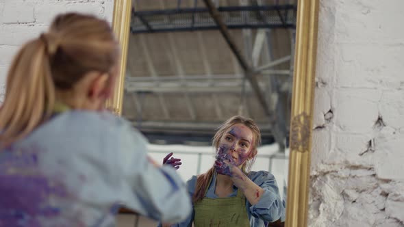 Woman Cleaning Face From Paints in Front Mirror Using Napkin