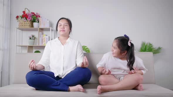 Mom and kid having meditation activity on the weekend together. Kid laughing mom
