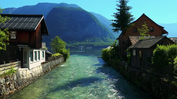 River Flowing Between Houses in Historical Village - Mountain with Lake in the Background