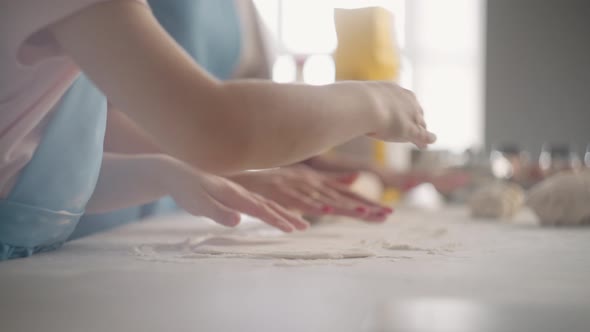 Cooking Food at Home Little Girl and Woman are Rolling Out Dough on Kitchen Table Closeup View