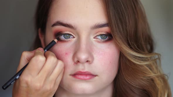 Girl Makeup Artist Paints the Eyes of a Young Girl