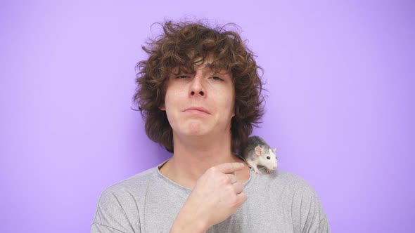 A Young Guy with Curly Hair Smiles at the Camera on an Isolated Background a Pet Rat is Sitting on