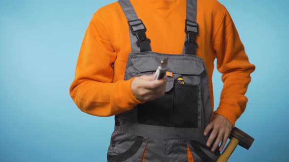 Unrecognizable Repairman in Industrial Work Clothes Giving Mock-up Knife To the Camera