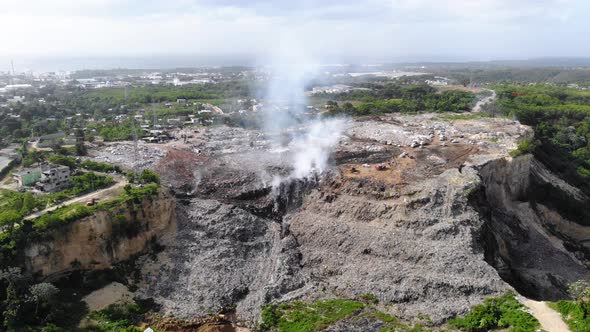 Aerial view around a junkyard fire, toxic smoke rising in middle of piles of junk, in Evento, Santo