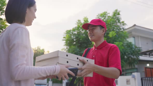 Asian deliver man worker in red color uniform handling bag of food drliverly give to young customer.