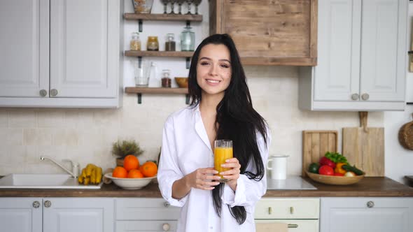 Happy Healthy Lifestyle. Woman Smiling With Fresh Orange Juice In Hands On Kitchen.