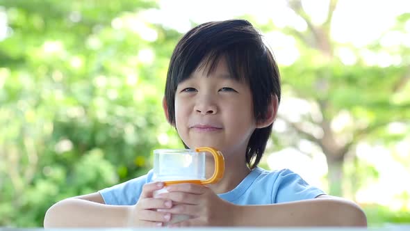 Cute Asian Child With A Glass Of Milk And Licking Lip