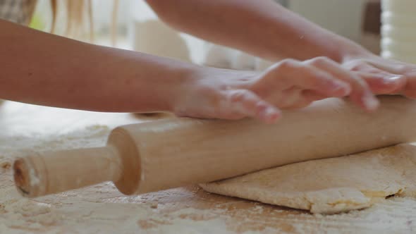 Closeup of Child Hand Roll in Flour Stroking Dough Using Rolling Pin in Home Kitchen