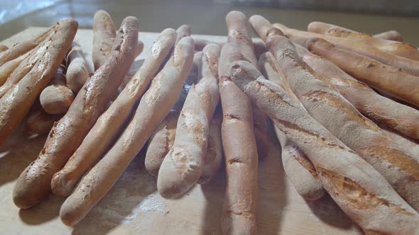Fresh Baked Long Baguette Breads Lie on the Wooden Table Sprinkled with Flour in a Pile