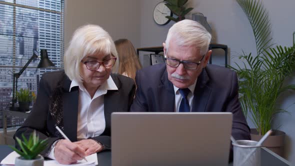 Senior Man Boss with Woman Colleague Working in Office Secretary Relaxing with Electric Fan