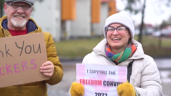 A Man and a Woman in Warm Clothes Hold Signs with the Inscriptions Thank you Truckers and Freedom