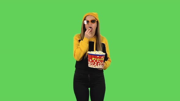 Modern Girl in Yellow Hat in 3D Glasses Is Watching an Exciting Movie and Eating Popcorn. Green