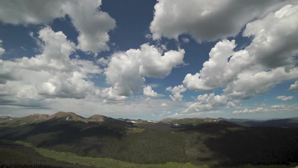 Time lapse of puffy clouds above mountain range and valley below