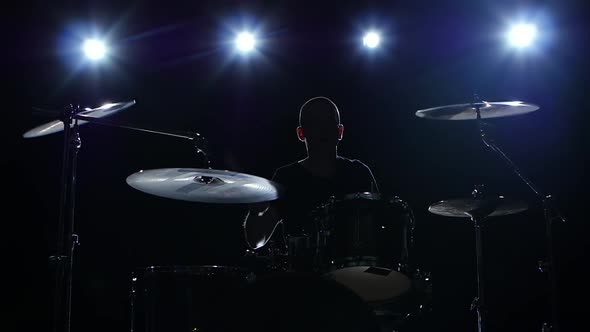 Drummer Plays the Melody on the Drums Energetically. Black Background, Back Light, Silhouette, Slow