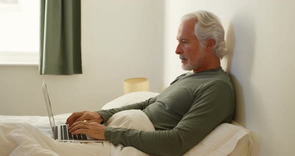 Senior Man Using Laptop on Bed in Bedroom 4k