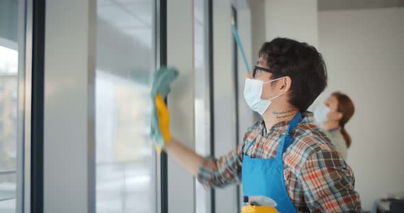 Team of Commercial Cleaners in Safety Mask Working in Office Cleaning Windows