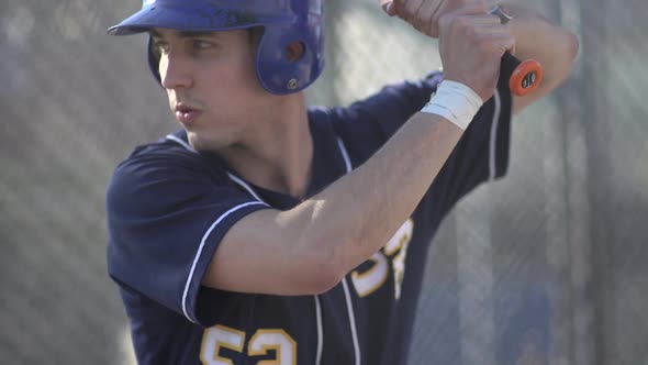 A young man practicing baseball at the batting cages.