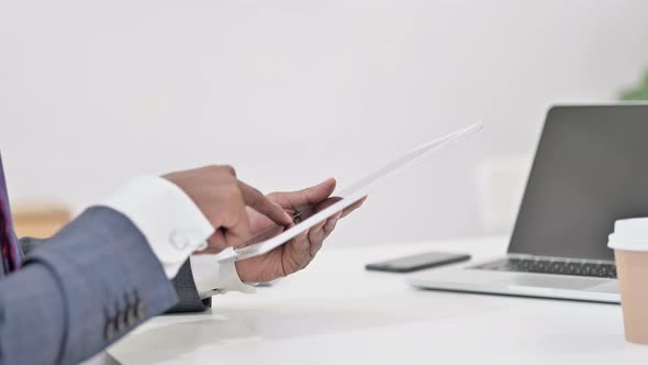 Close Up of Hands of African Businessman Working on Tablet 