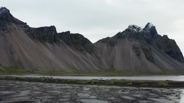 Drone Flight Of Car Driving Along Wet Dirt Track Road With Vestrahorn